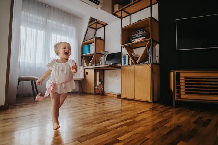 Child happily running across a beautifully installed hardwood floor